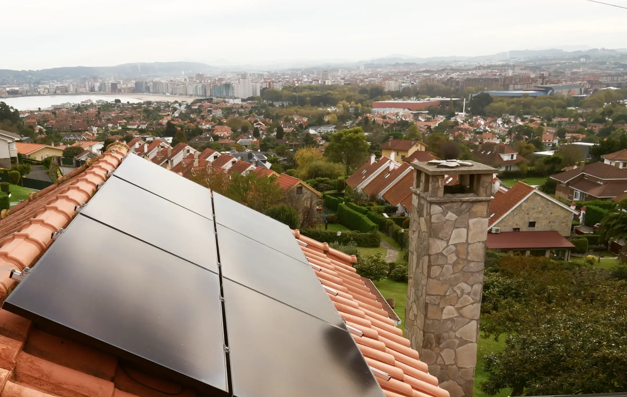 Imagen de un tejado con placas solares y de fondo una ciudad